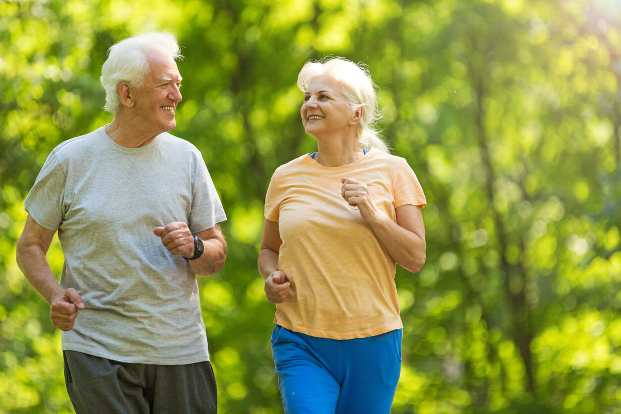 Older man and woman keeping their bodies in motion by running together. Leading to life long fitness.