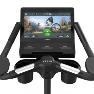 Console view of a Performance Series Upright Bike, featuring a touchscreen display with workout options and virtual scenery, surrounded by handlebars and cup holders.