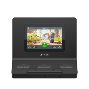 A black TRUE fitness equipment console displaying a screen with a running shoe stepping outdoors, options for classes and quick start, and caution/warning labels below the screen.